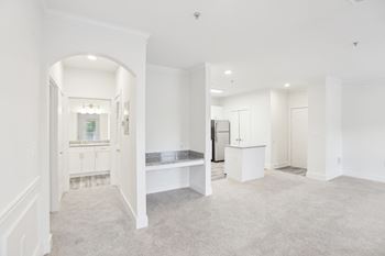 A white room with a carpeted floor and a bench.